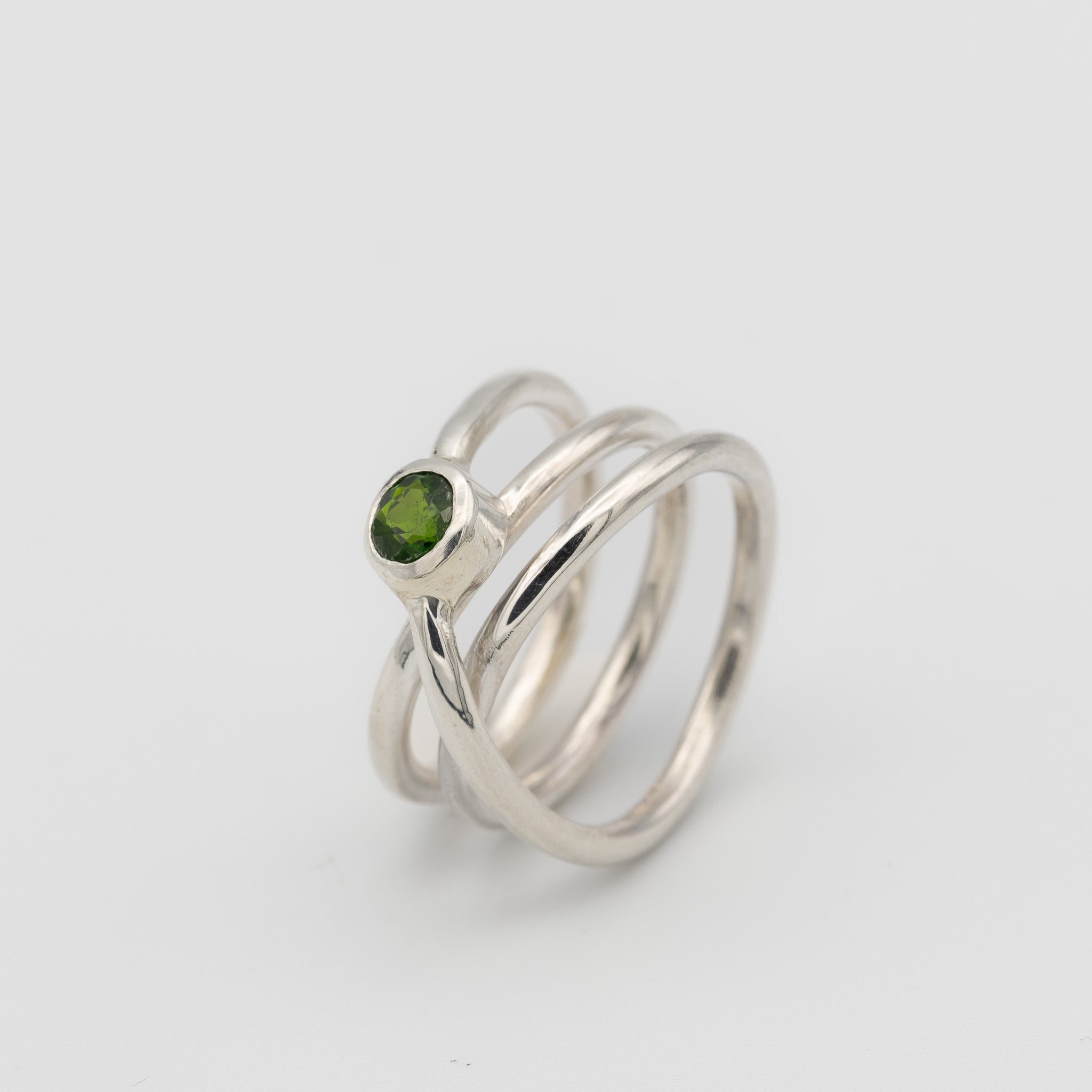 silver handmade ring in a shape of an orbit with a single gemstone set. now single silver wire wrapped and creating coils.