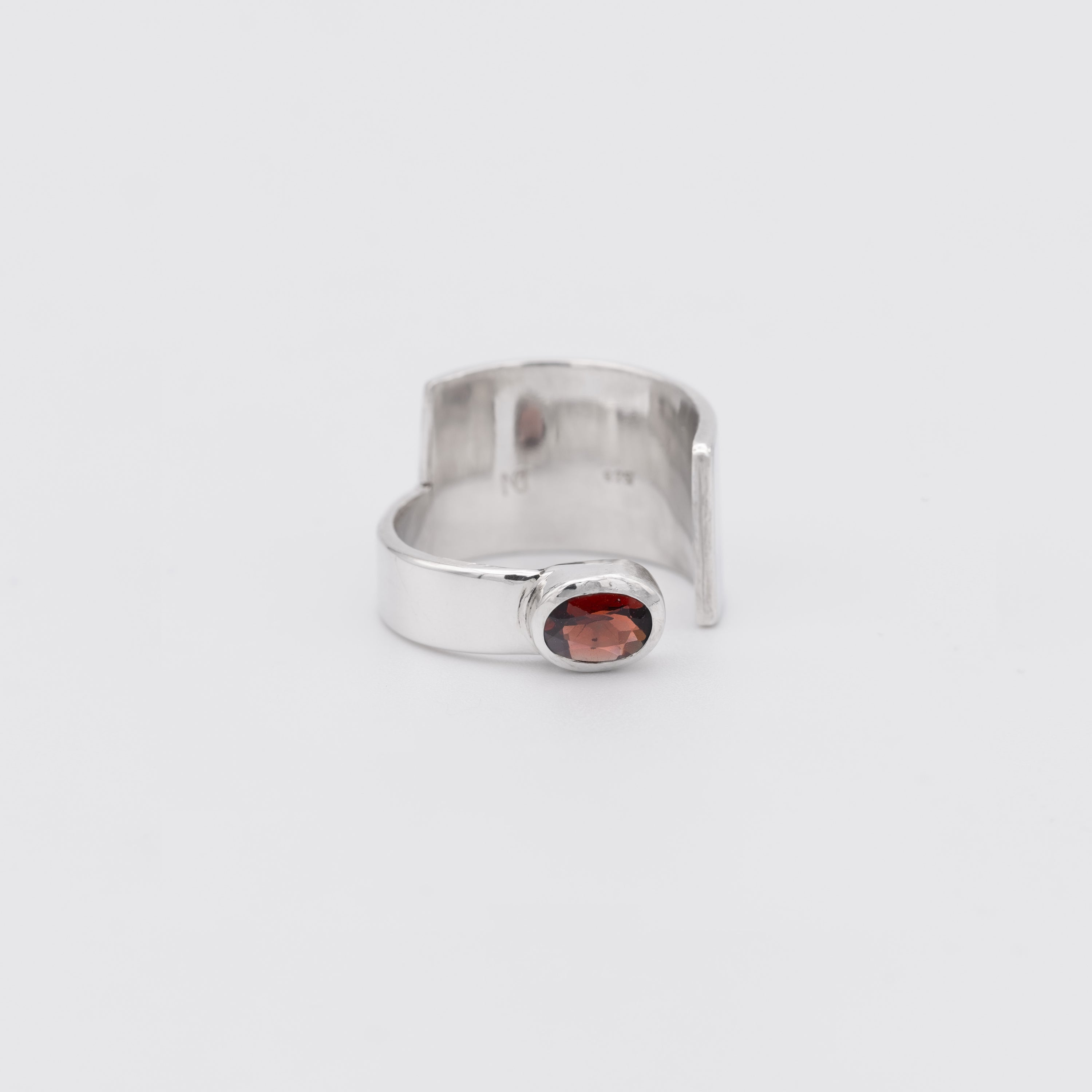 Silver ring with a red gemstone on a white background
