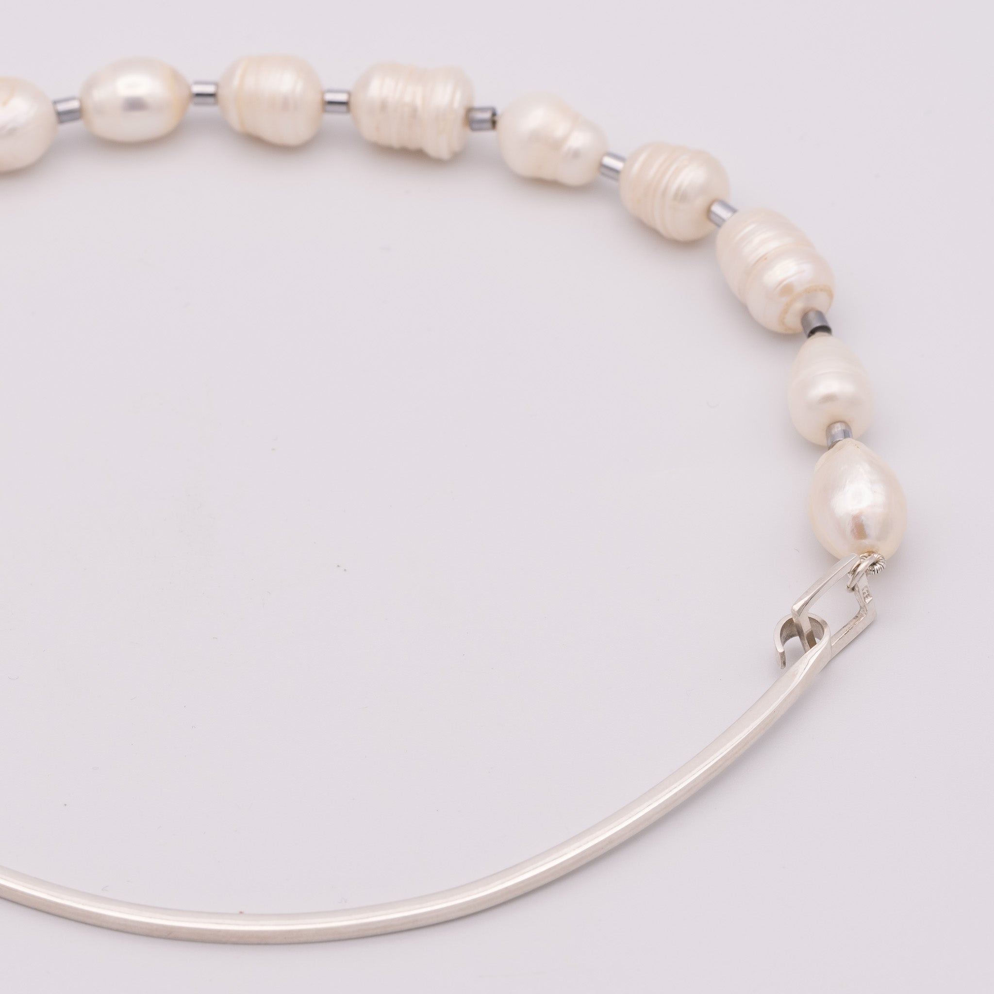 Pearl necklace with silver clasp on a light gray background