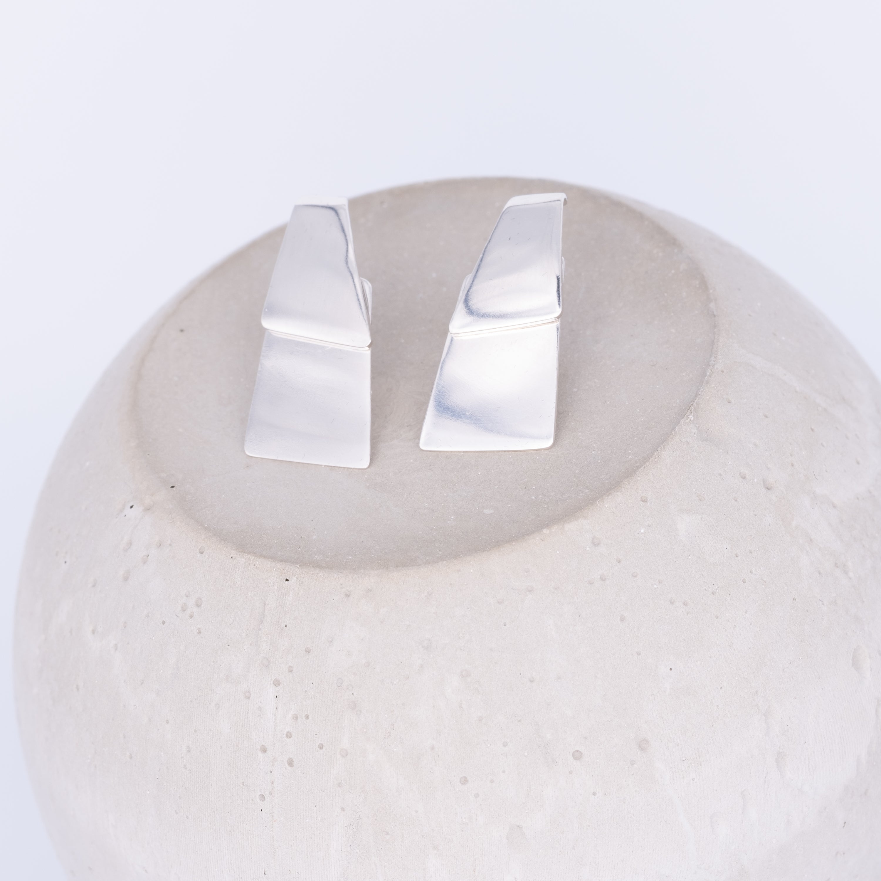Pair of silver earrings on a white stone surface