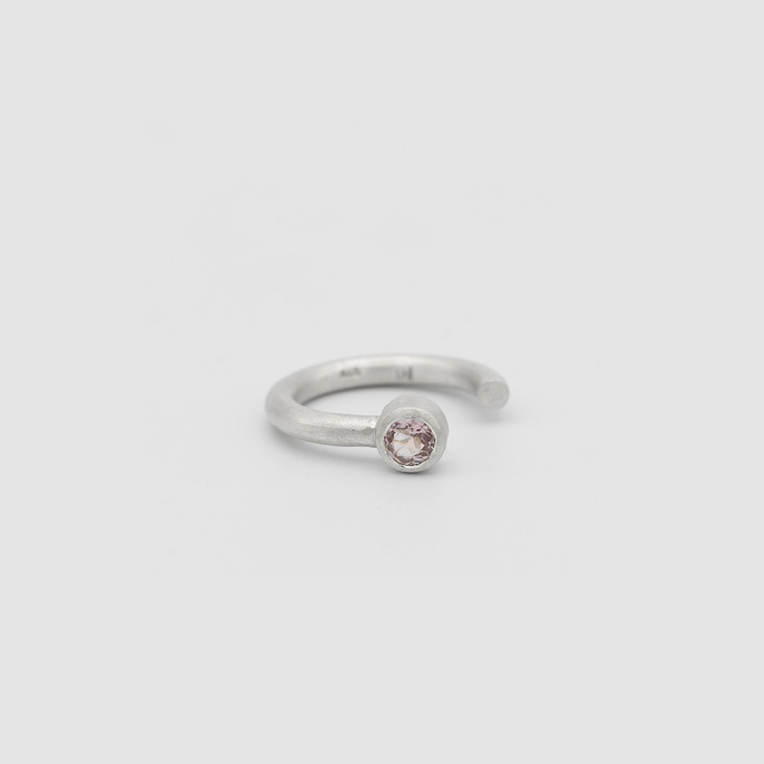 Silver ring with a pink gemstone on a light gray background