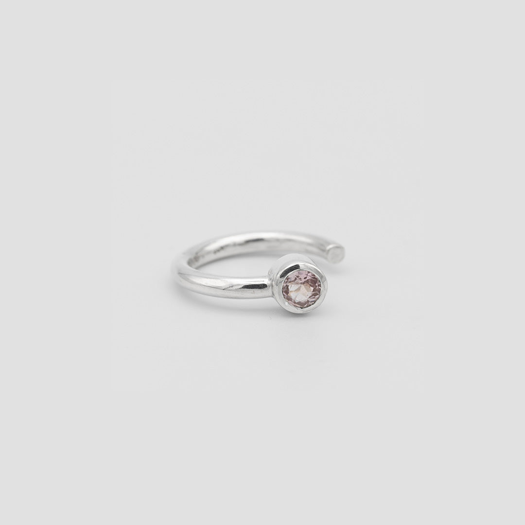 Silver ring with a pink gemstone on a light gray background