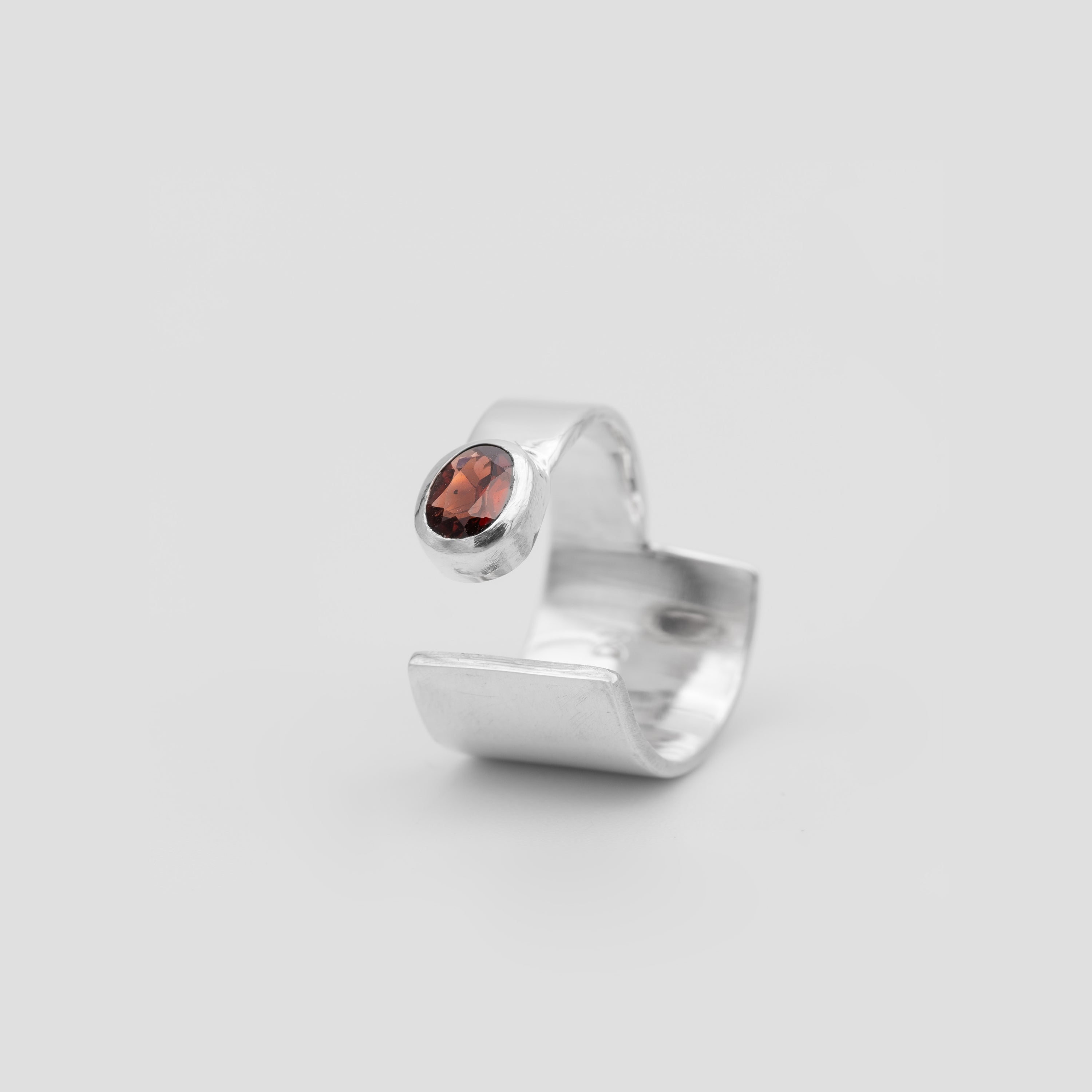 Silver ring with a red gemstone on a light gray background