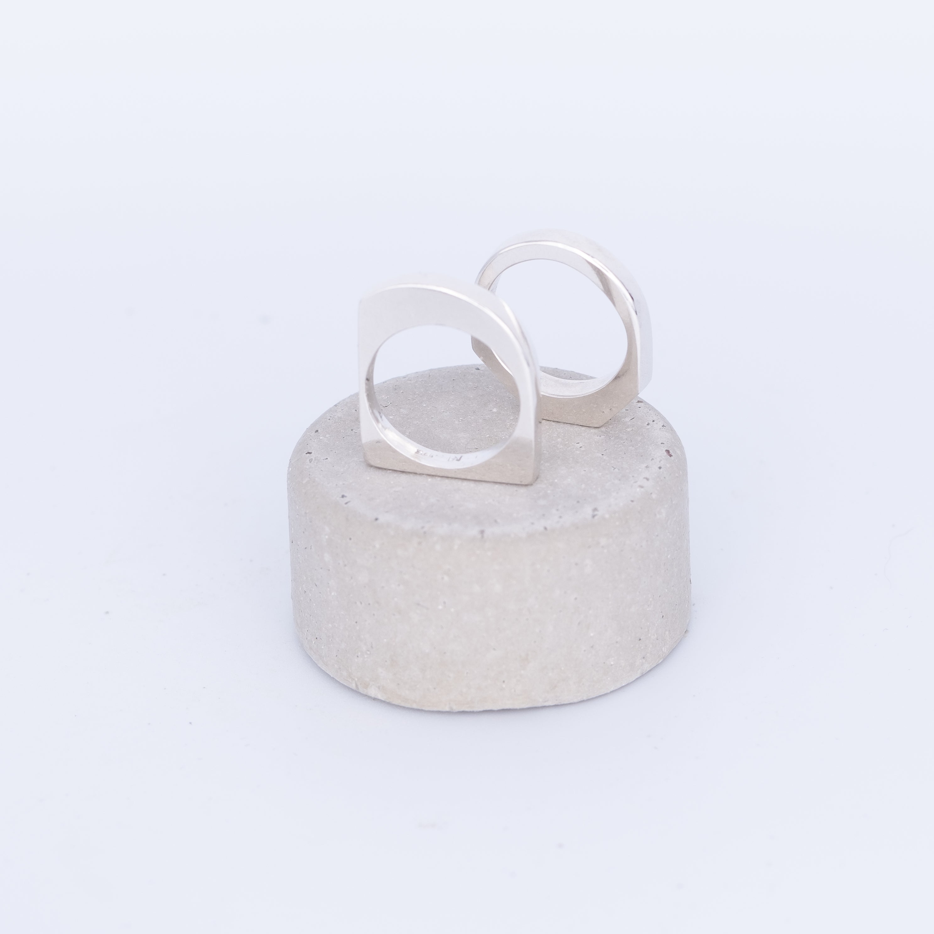 Silver ring on a textured gray stand against a white background