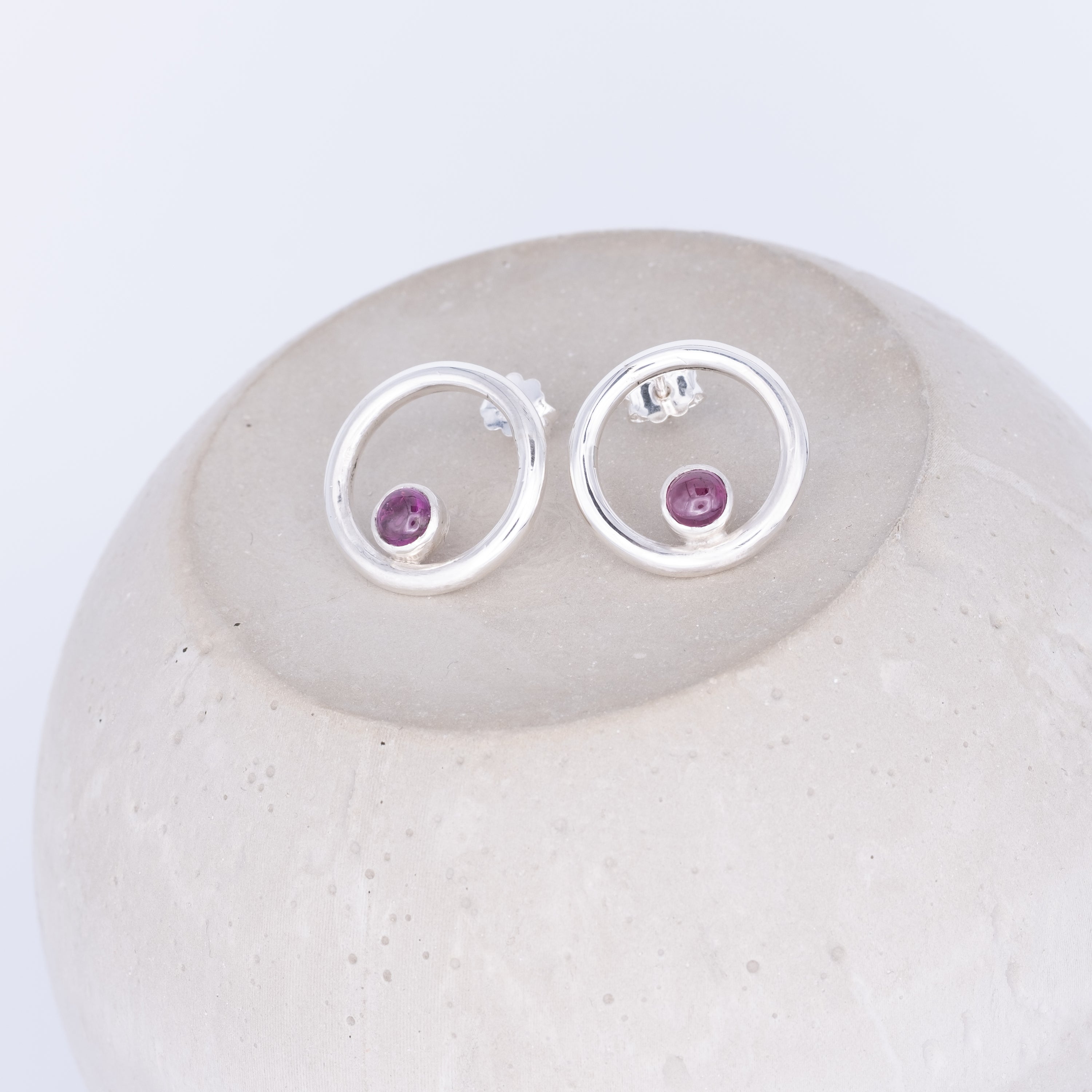Silver earrings with purple gemstones on a white stone tourmaline