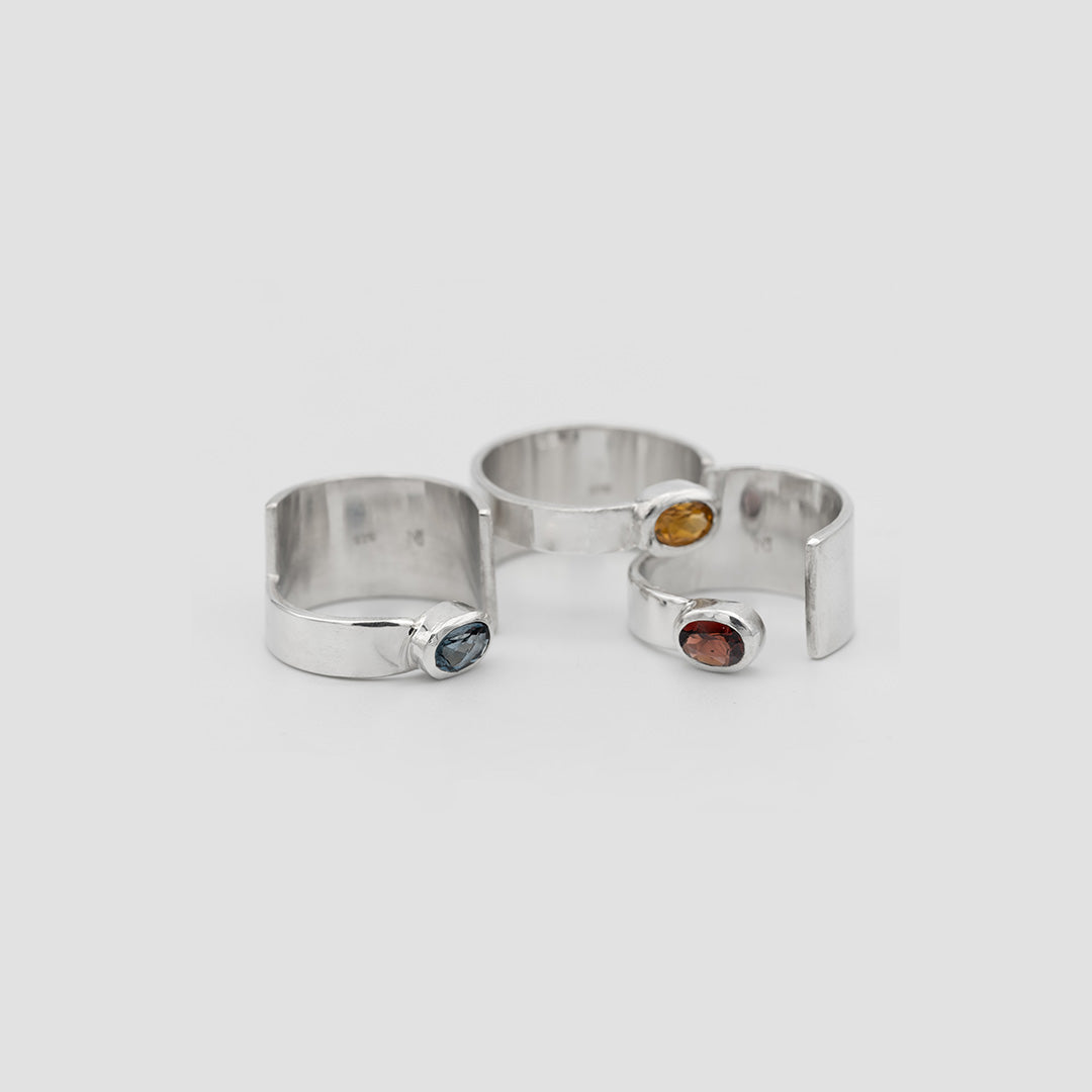 Three silver rings with gemstones on a light gray background