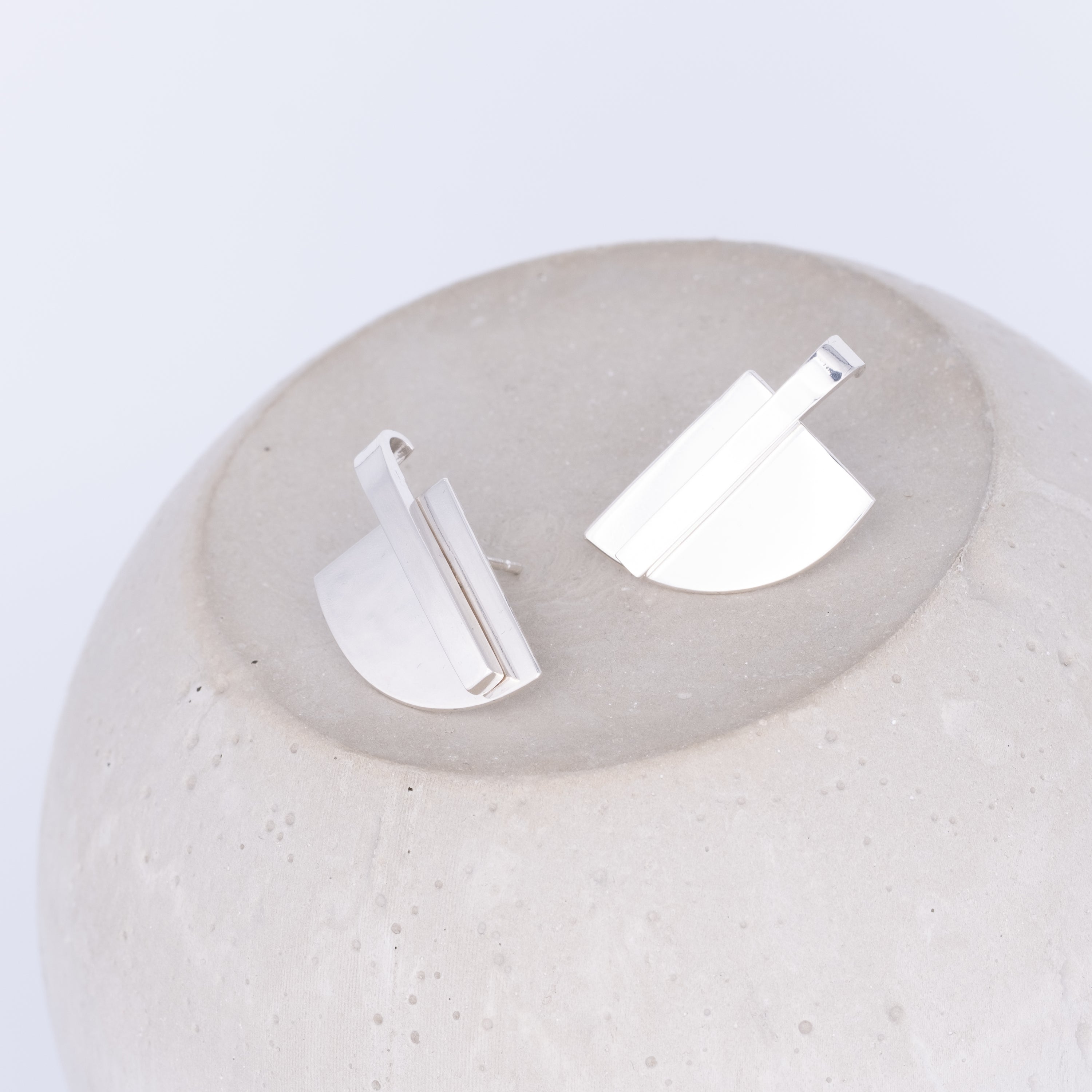 Silver earrings on a textured white surface