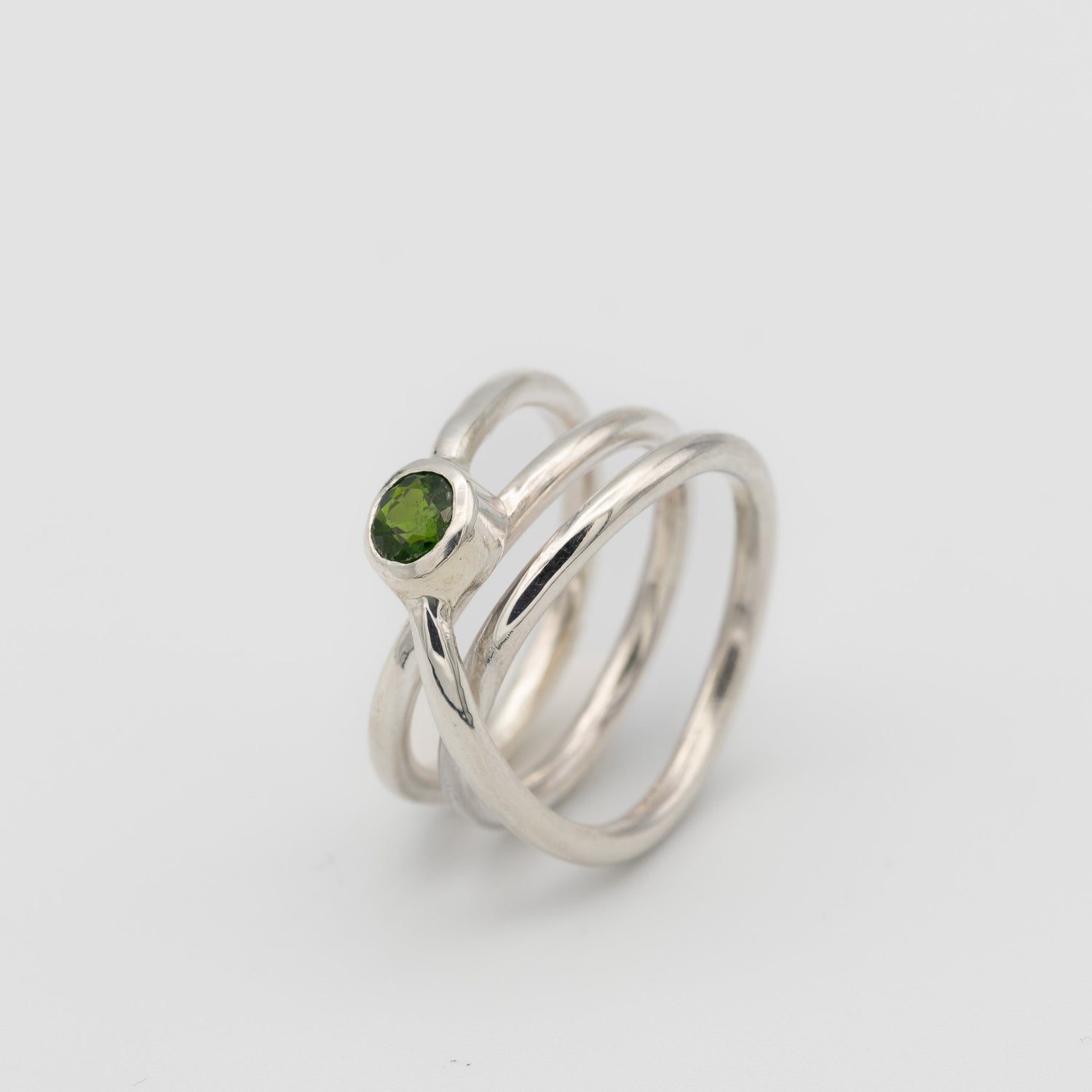 silver handmade ring in a shape of an orbit with a single gemstone set. now single silver wire wrapped and creating coils. 