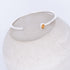 Silver bracelet with a small orange gemstone on a white background