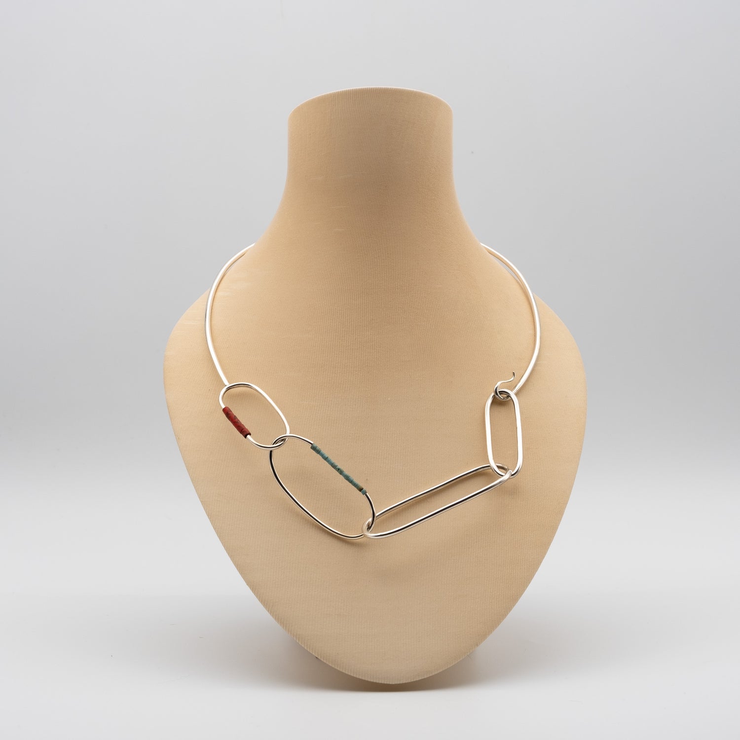 Silver necklace on a beige mannequin bust against a light gray background