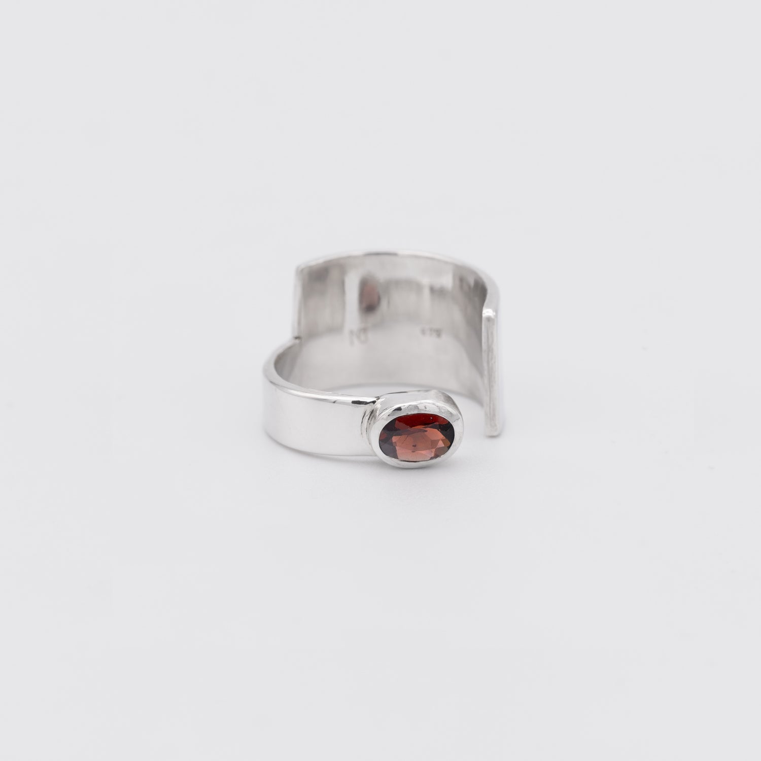 Silver ring with a red gemstone on a white background