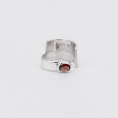 Silver ring with a red gemstone on a white background