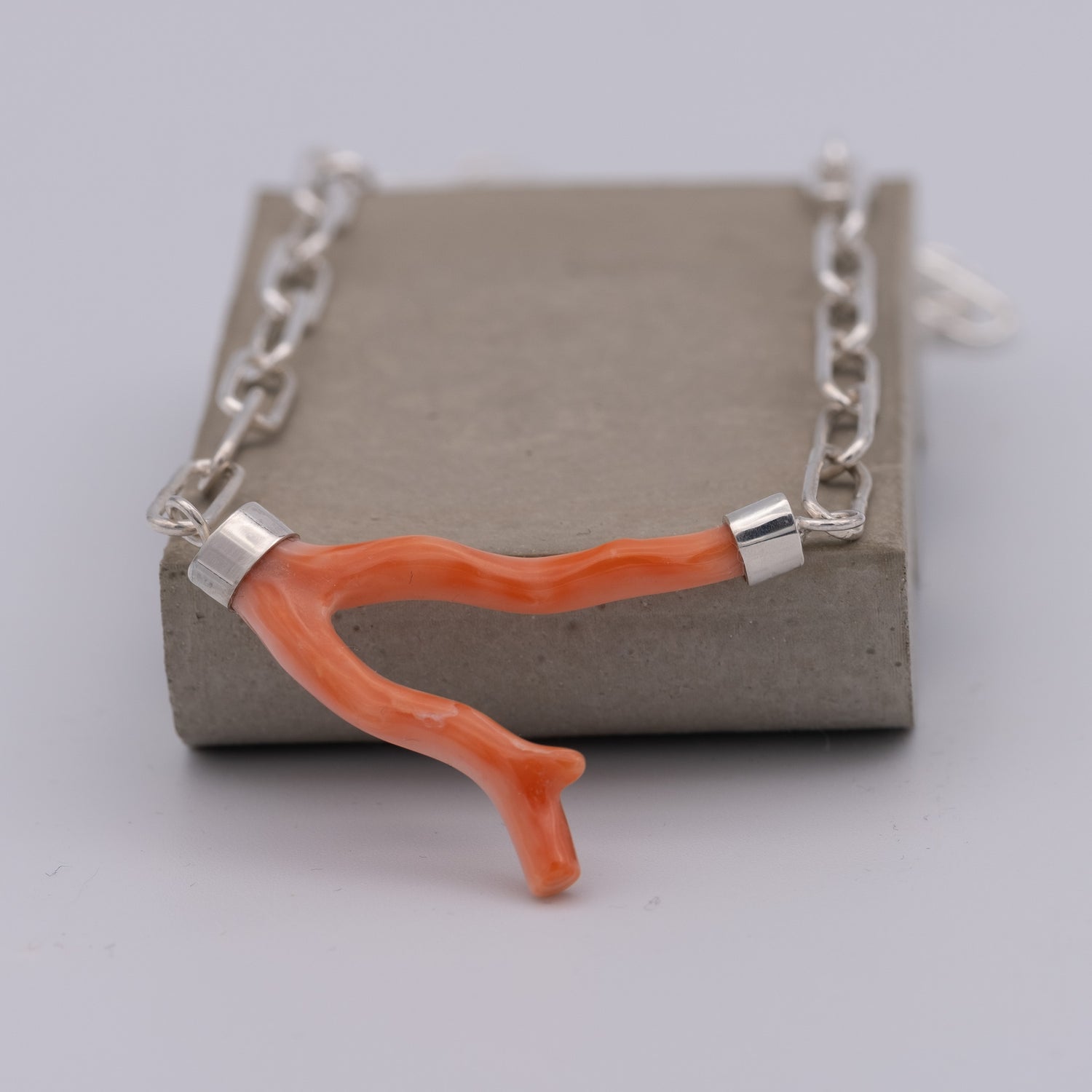 Necklace with an orange coral branch pendant on a gray background