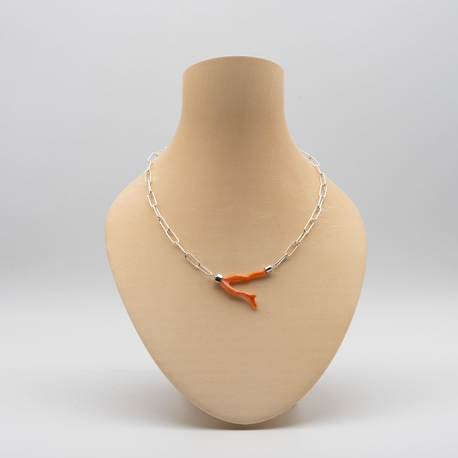 Necklace with an orange coral branch on a mannequin bust against a white background