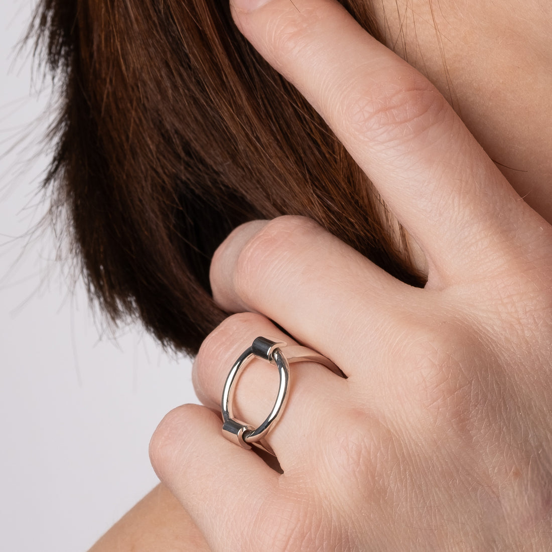 Close-up of a hand wearing a silver ring with a minimalistic design.