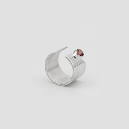 Silver ring with a red gemstone on a light gray background