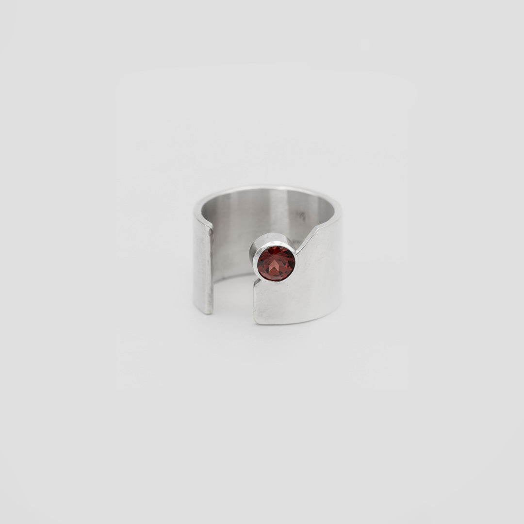 Silver ring with a red garnet gemstone on a light gray background