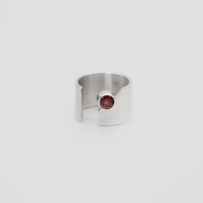 Silver ring with a red garnet gemstone on a light gray background