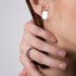 Close-up of a person wearing a silver hexagonal ring on a neutral background