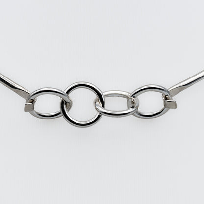 A close-up of a polished silver-tone metal chain with three interlocking oval links and small square connector pieces, shown against a plain light gray background.