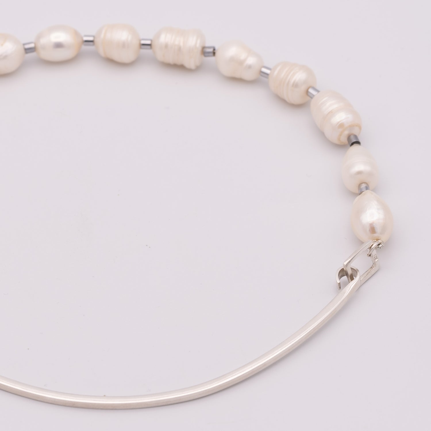 Pearl necklace with silver clasp on a light gray background
