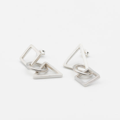 A pair of silver geometric dangle earrings featuring interlocking open triangles and squares, photographed on a clean white background.