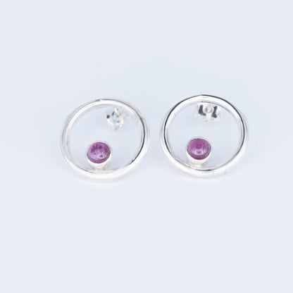 Silver earrings with pink gemstones on a light gray background