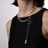 Pearl necklace with a pendant on a person wearing a black top against a plain background