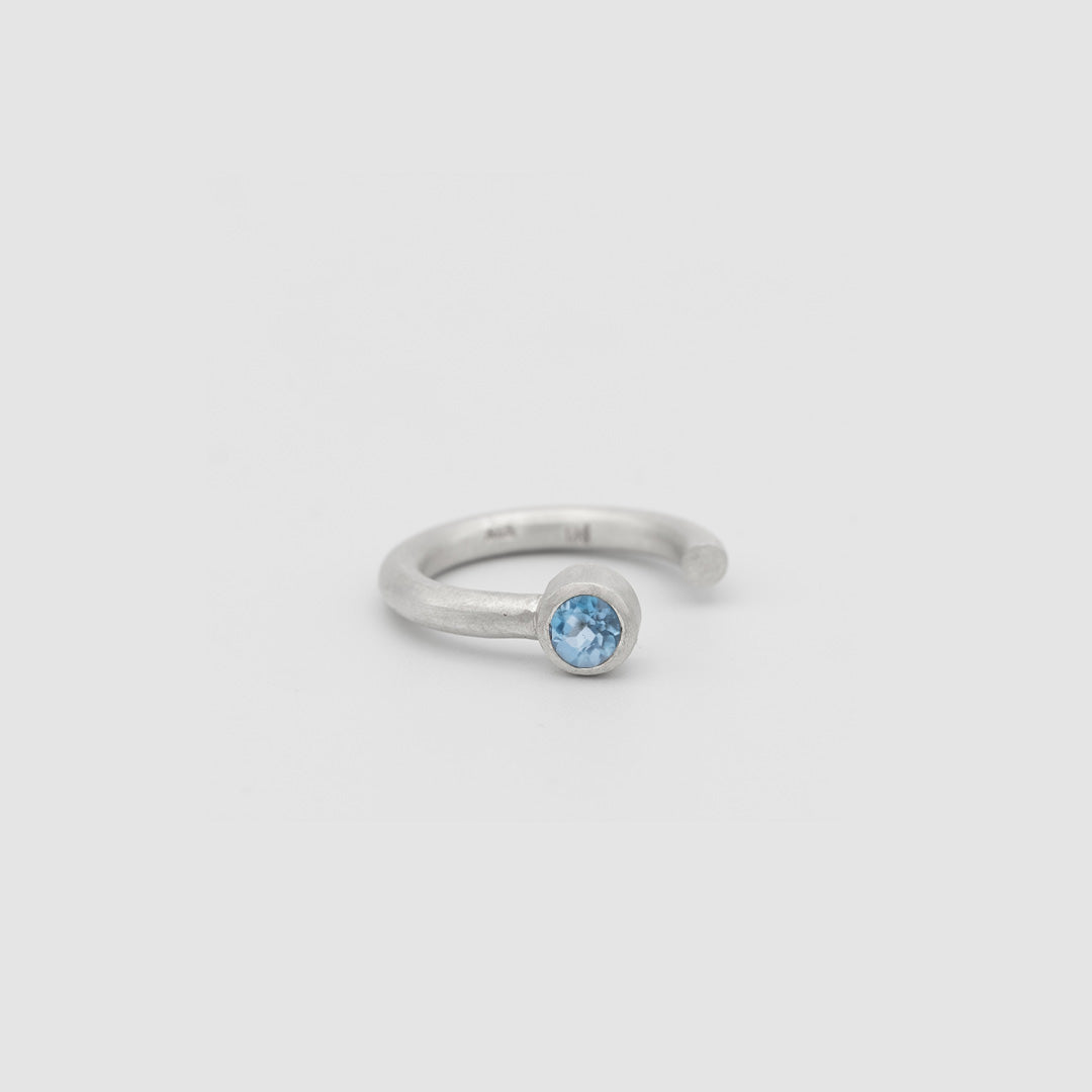 Silver ring with a blue gemstone on a light gray background
