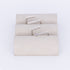 Set of silver earrings on a textured beige card against a white background
