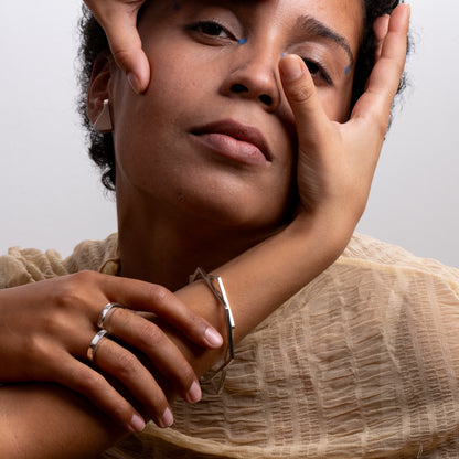 Woman wearing a bracelet and rings with a neutral background