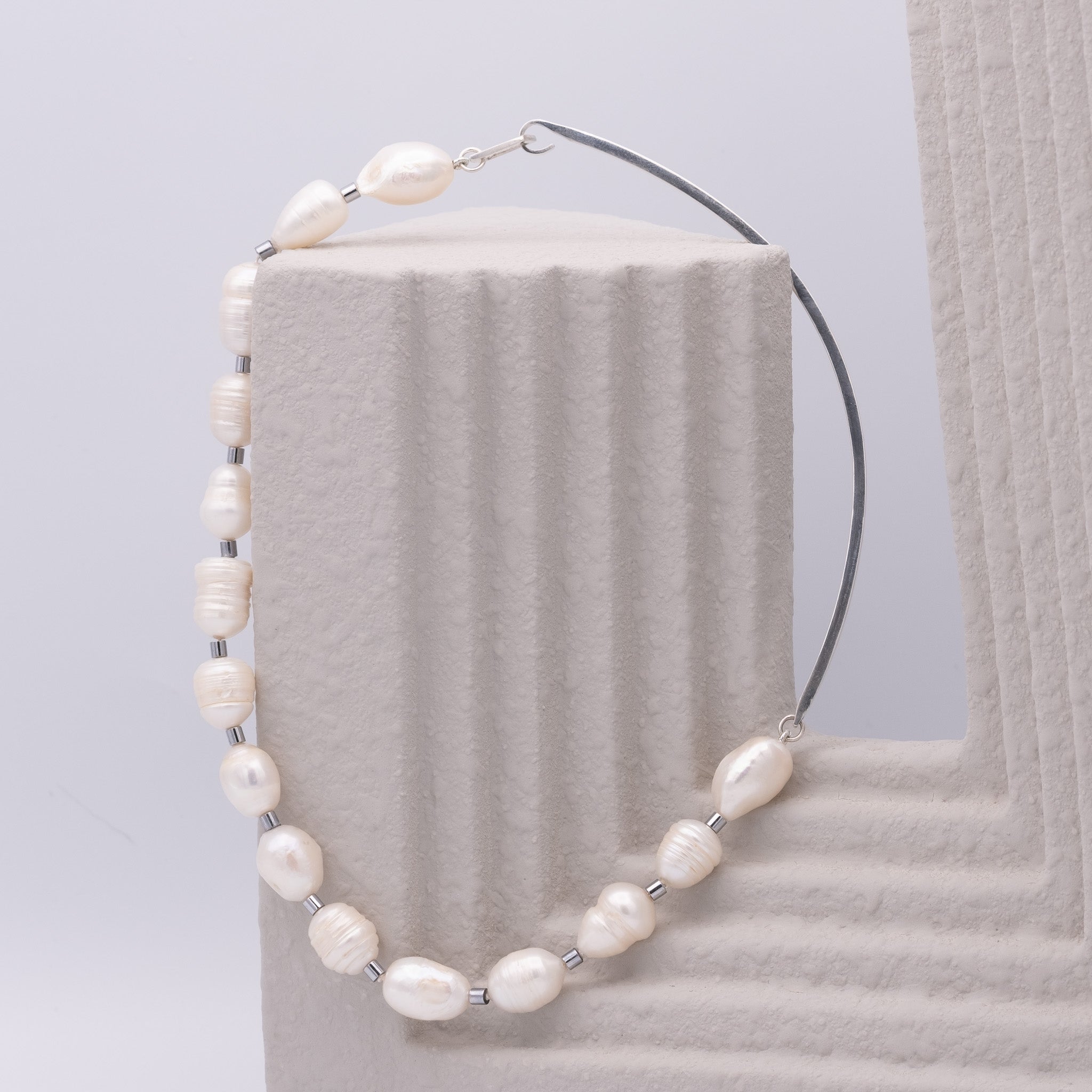 Pearl necklace on a textured gray surface with a light gray background