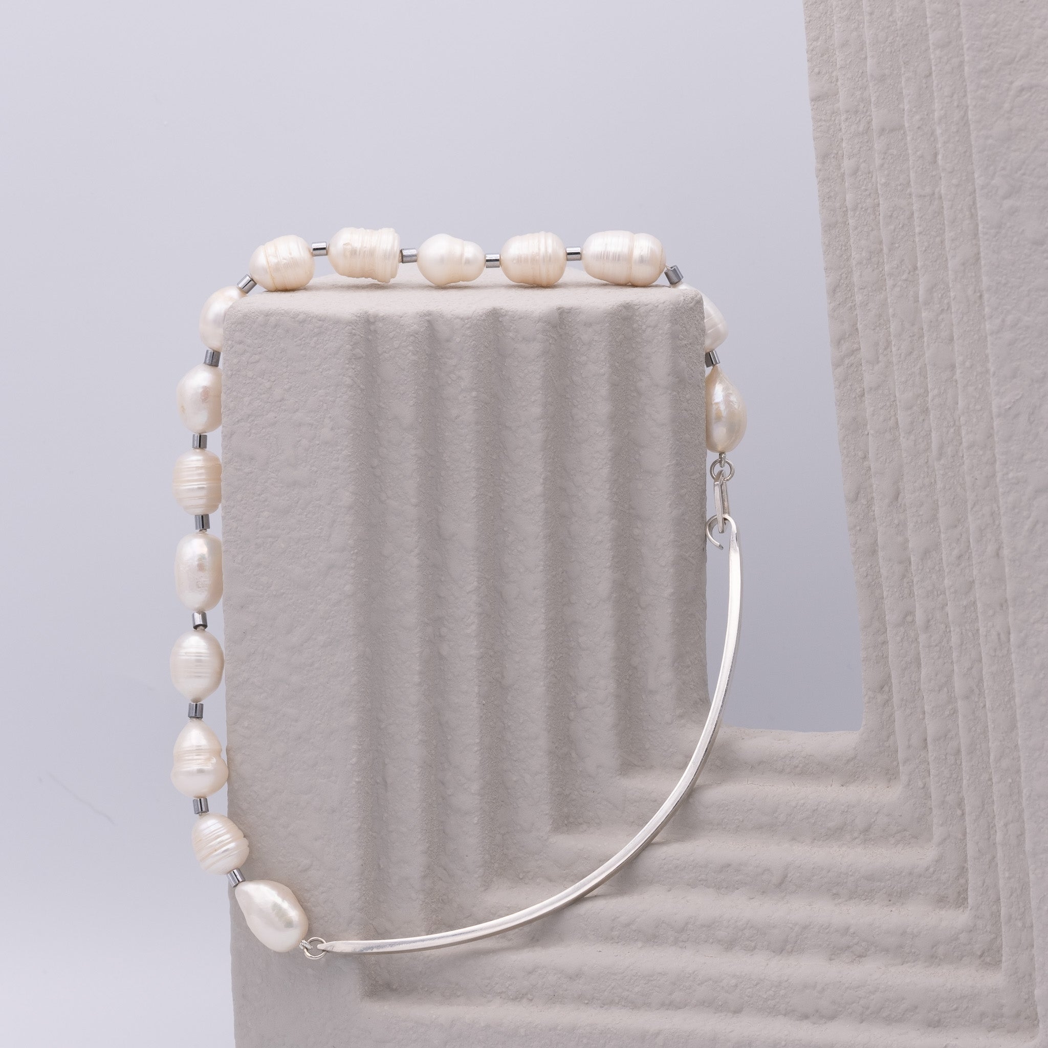 Pearl necklace  on a textured surface with a light gray background