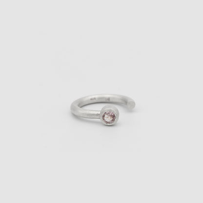 Silver ring with a pink gemstone on a light gray background