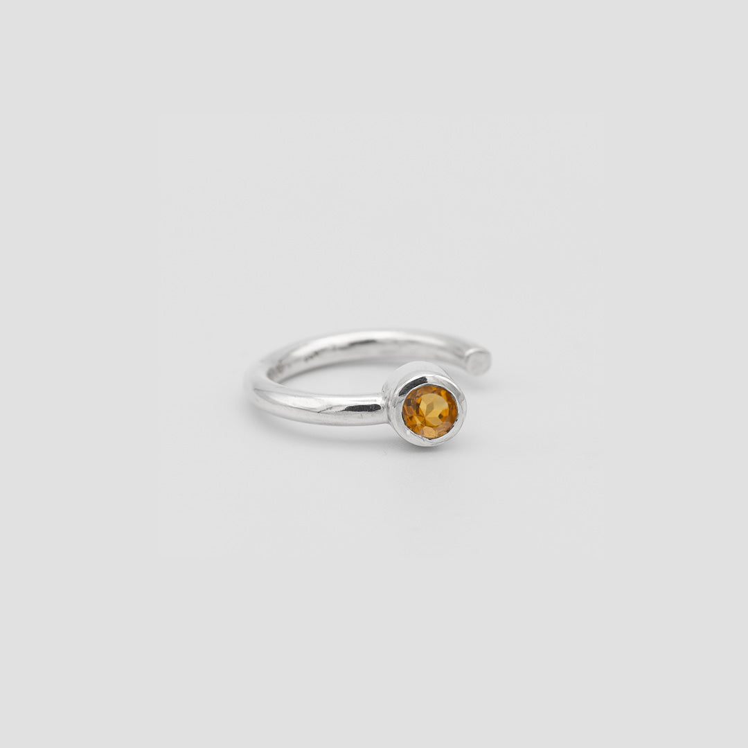 Silver ring with a yellow gemstone on a light gray background