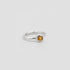 Silver ring with a yellow gemstone on a light gray background