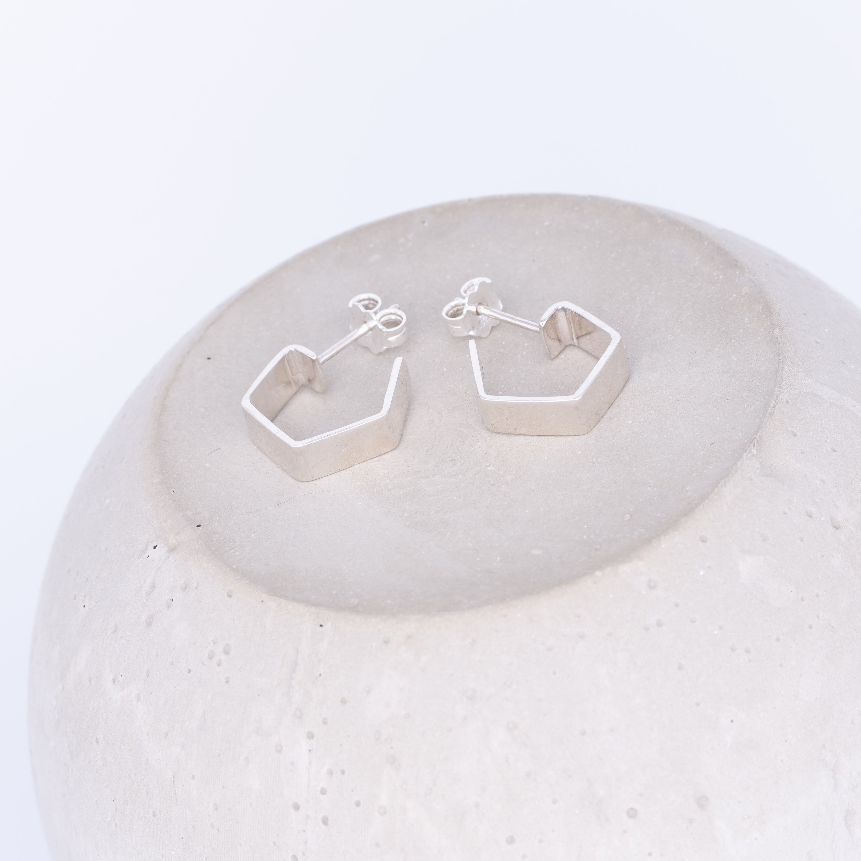 Silver geometric earrings on a textured white surface