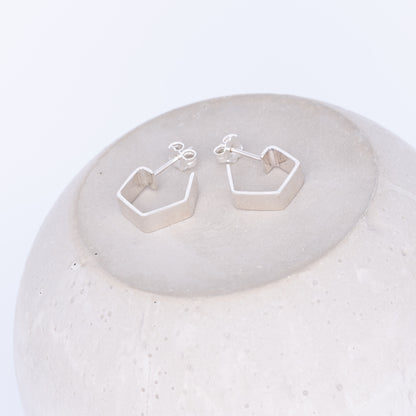 Silver geometric earrings on a textured white surface