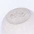 Silver geometric earrings on a textured white surface