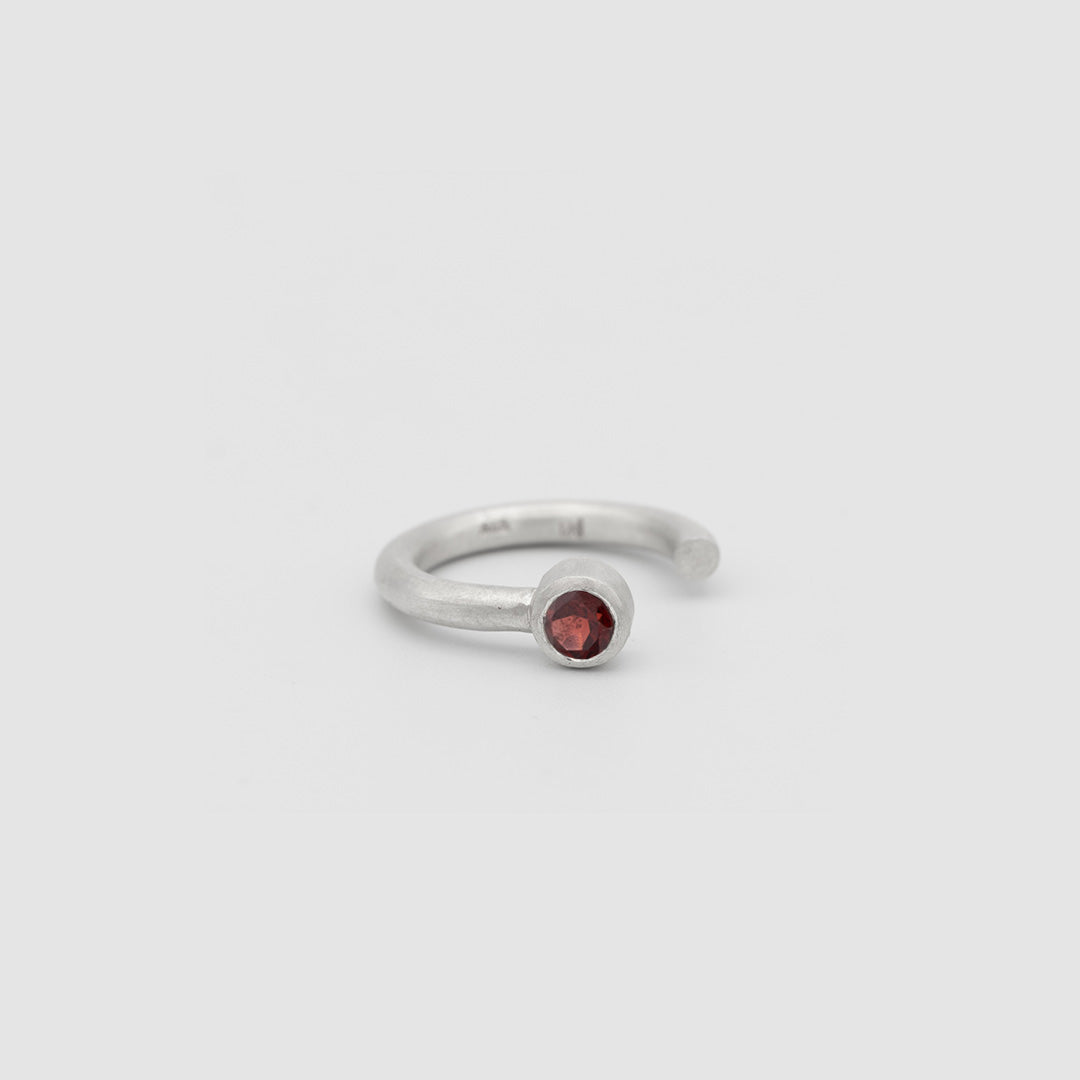 Silver ring with a red gemstone on a light gray background
