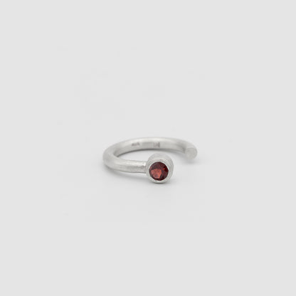 Silver ring with a red gemstone on a light gray background