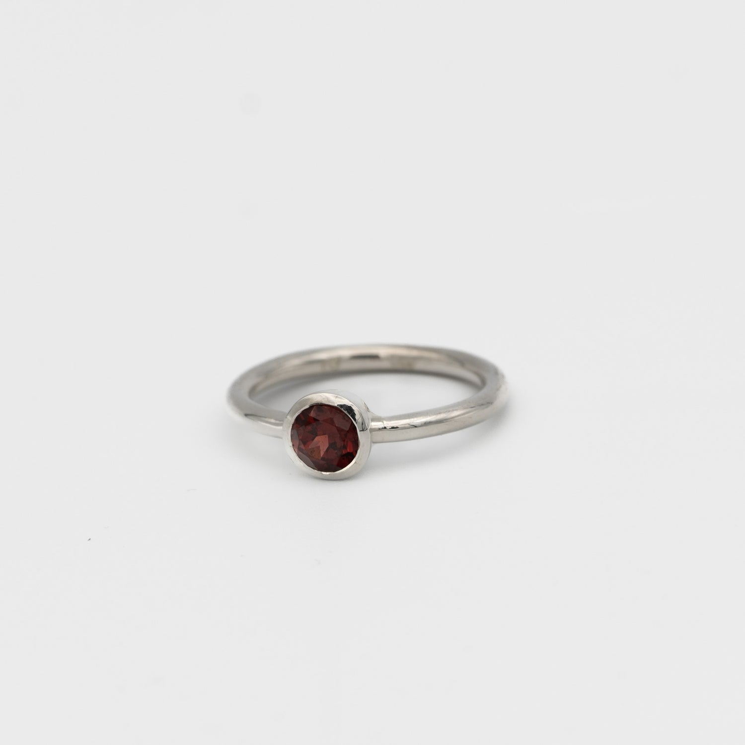 Silver ring with a red gemstone on a light gray background