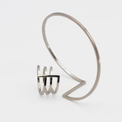 A pair of minimalist silver jewerly. One ring and next to it one bangle-