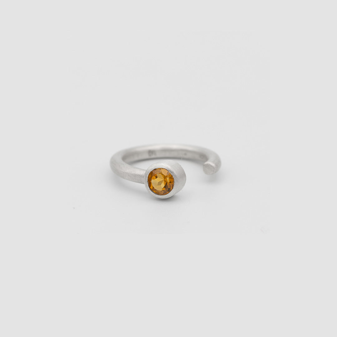 Silver ring with a yellow gemstone on a light gray background