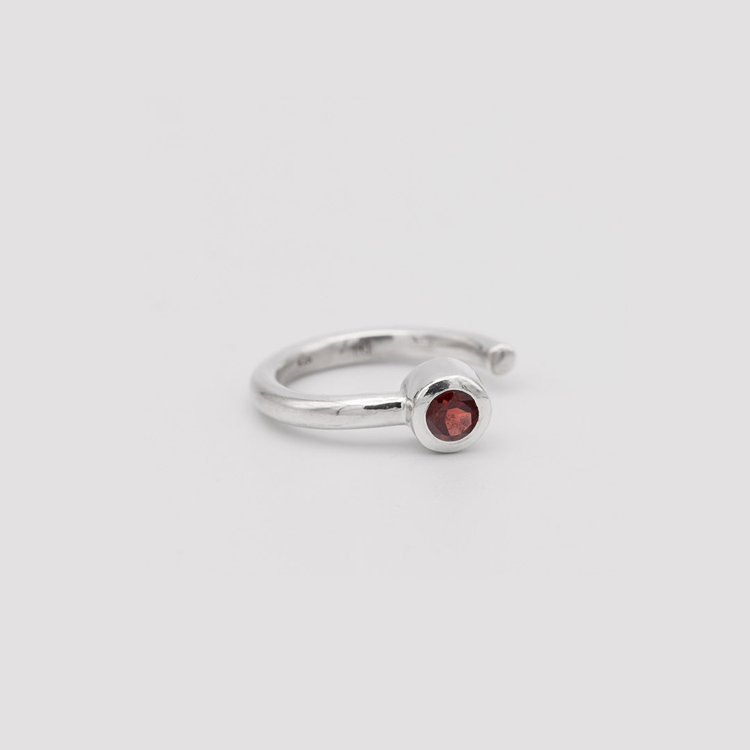Silver ring with a red gemstone on a light gray background