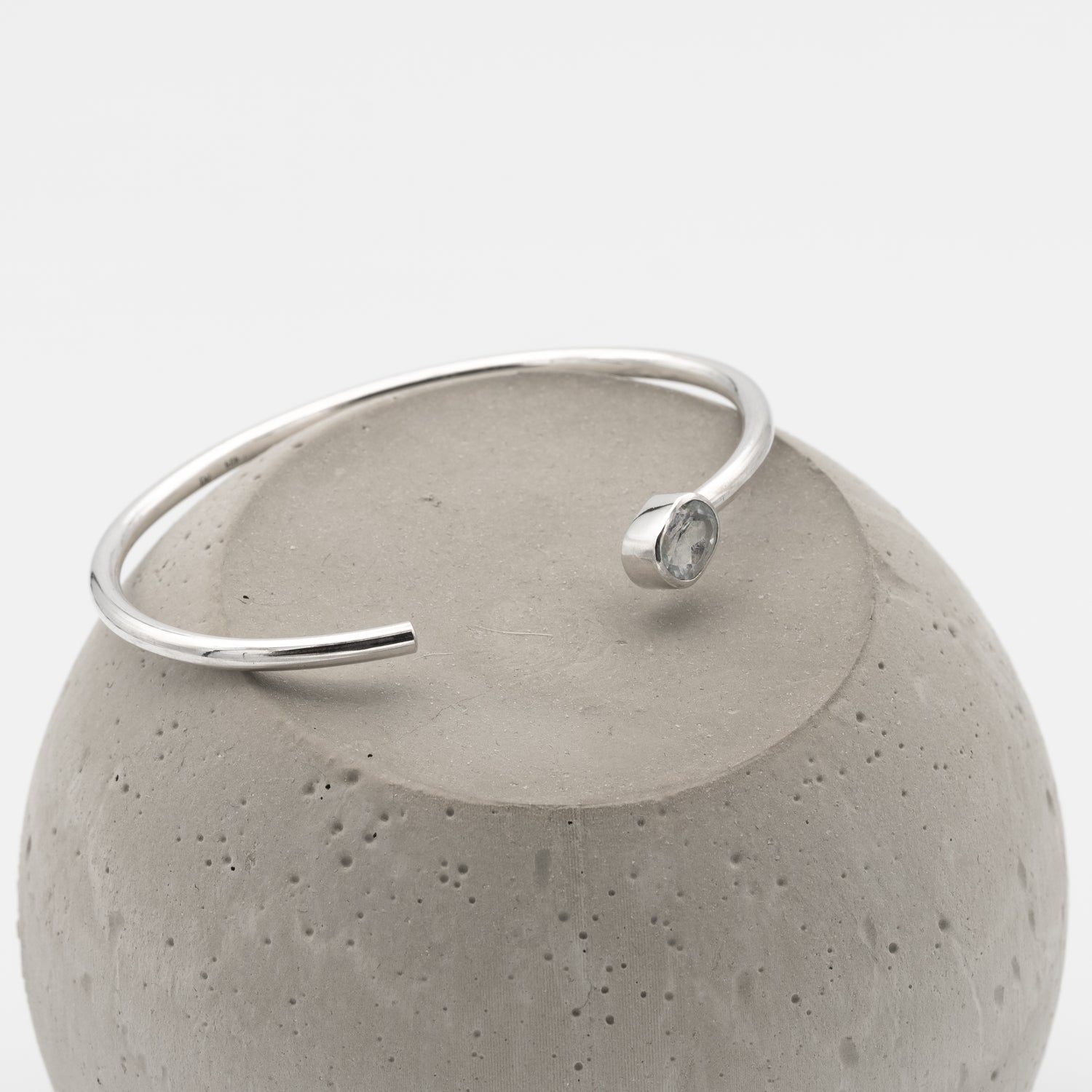 Silver bracelet with a gemstone on a concrete block