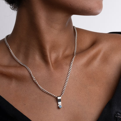 Close-up of a person wearing a silver chain necklace with a small pendant.