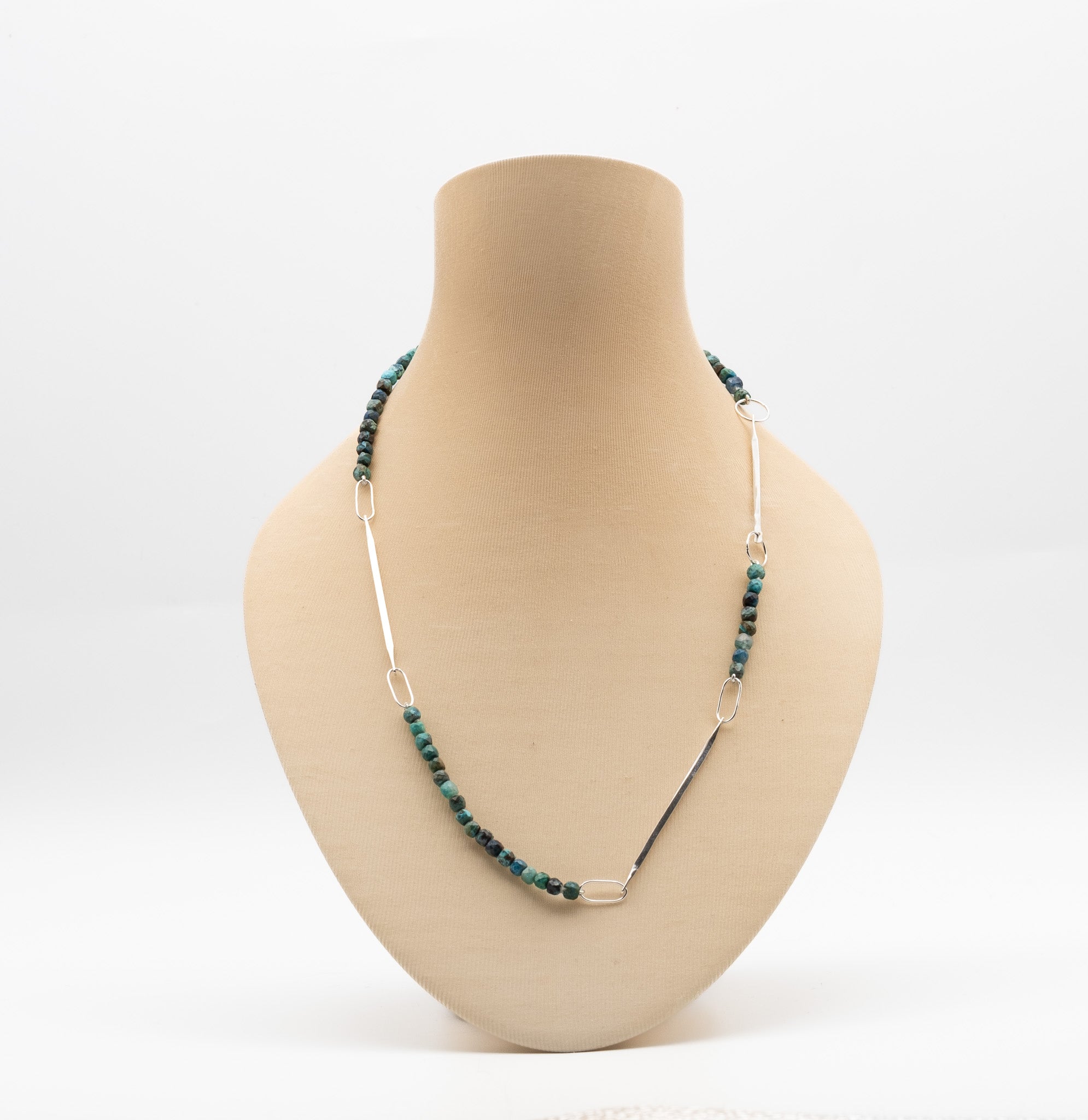 Necklace with green beads on a mannequin bust against a white background