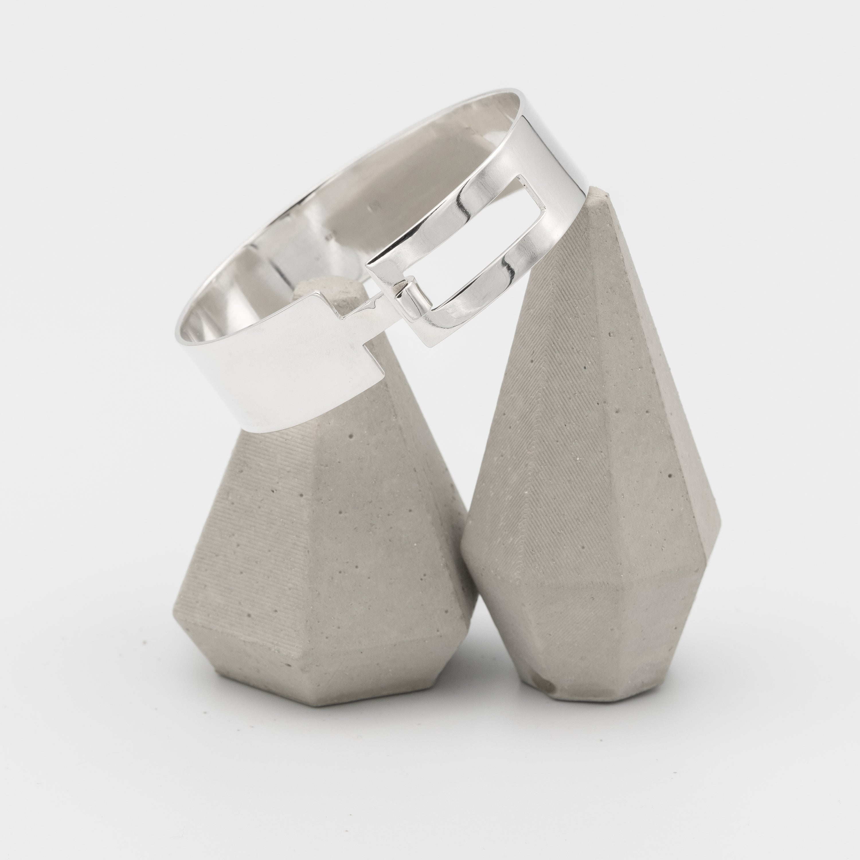 Silver bracelet with concrete-like ends on a white background