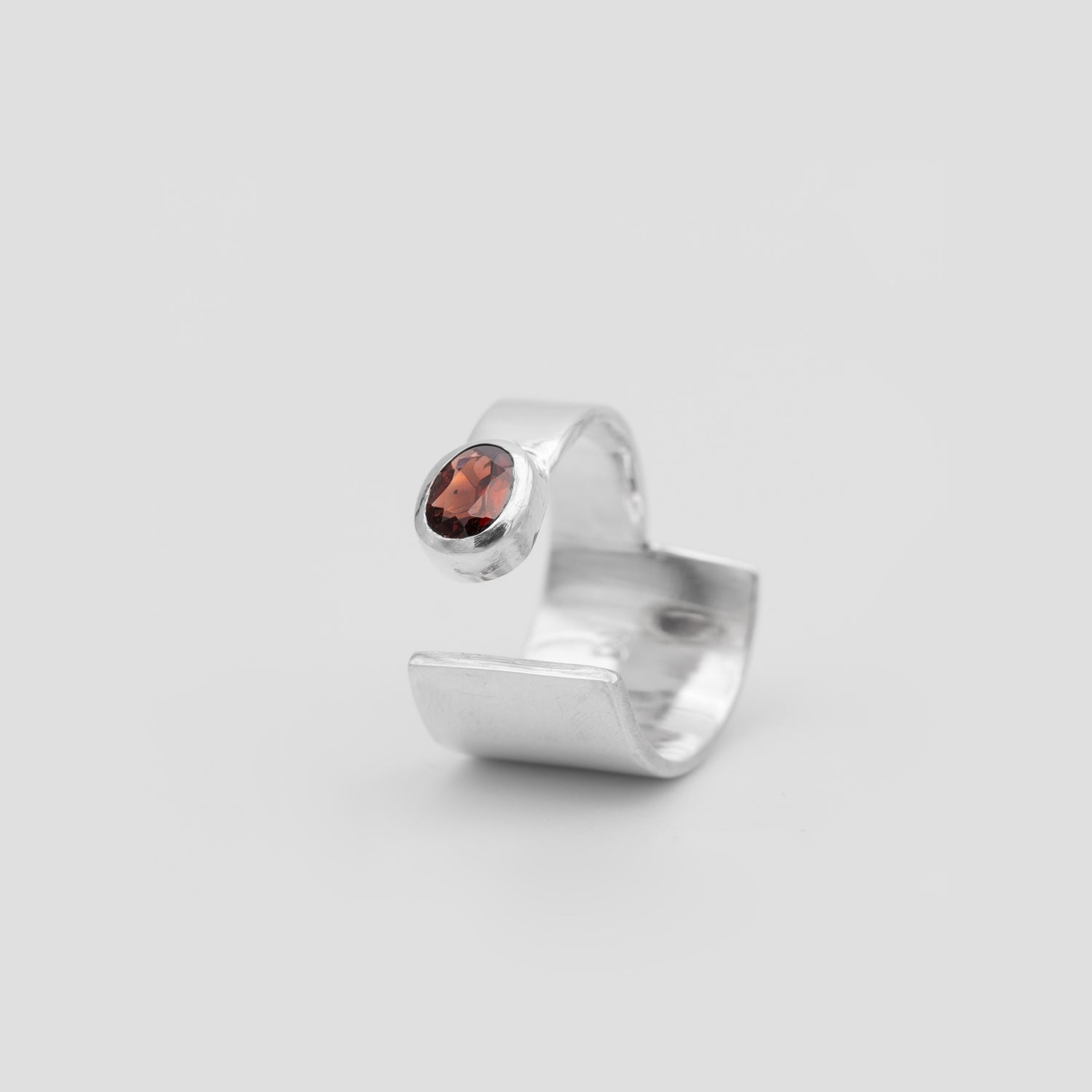 Silver ring with a red gemstone on a light gray background